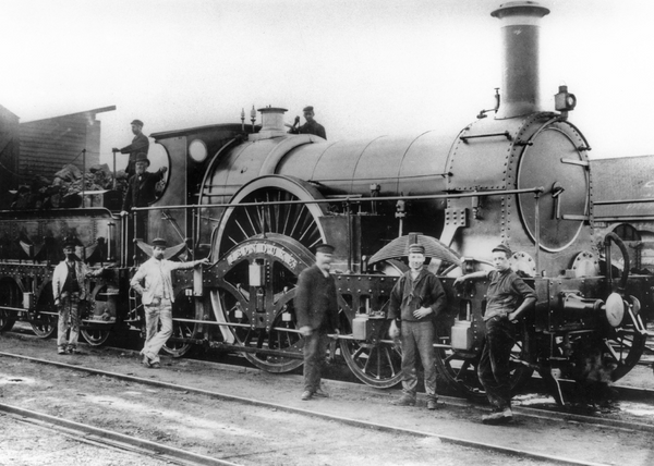 Railroad workers standing next to a steam engine